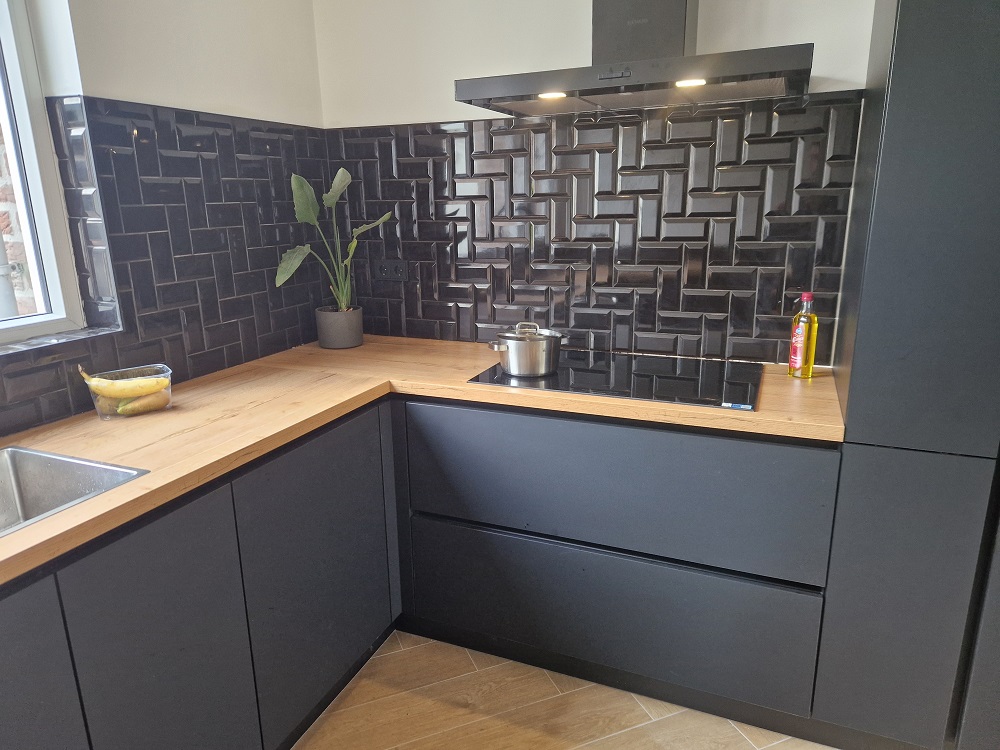 Keuken met zwart tegelwerk en houten werkblad